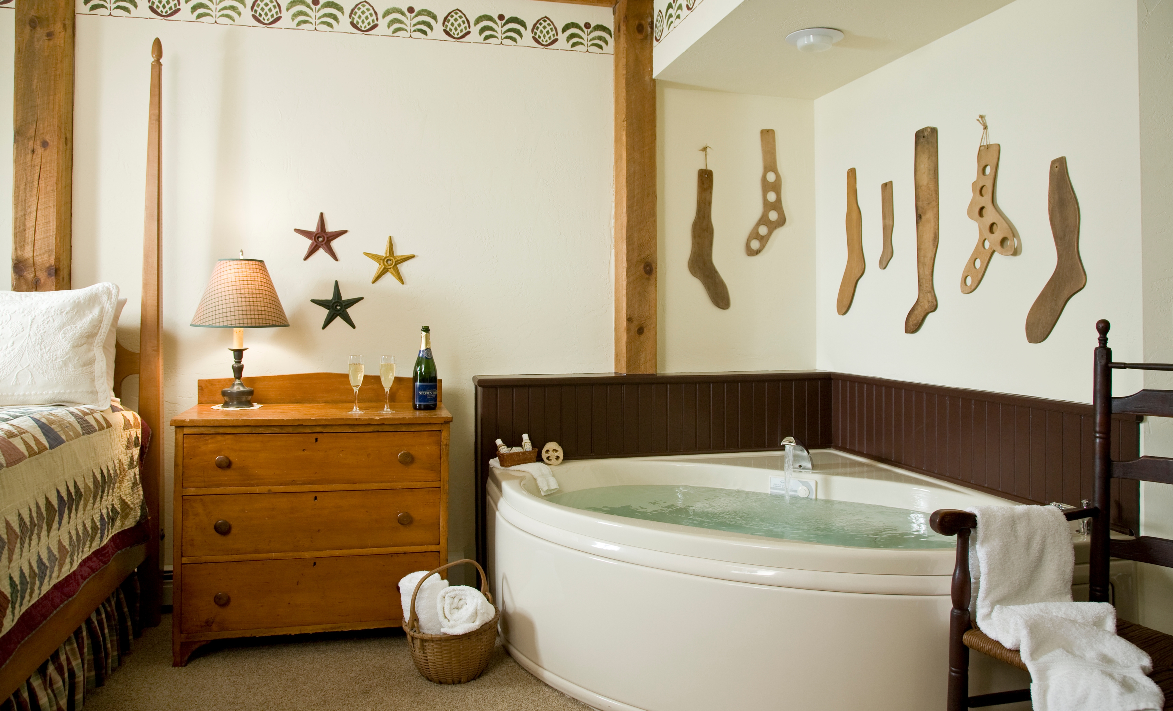 A large white whirlpool tub set against a dark wood wainscoted wall, decorated with several vintage wooden sock stretchers hanging above it.