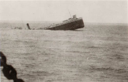 A partially submerged ship sinks in calm waters.
