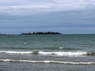 From the opposite shoreline the now darkened "bird cage" lighthouse in Baileys Harbor remains part of the tree line.